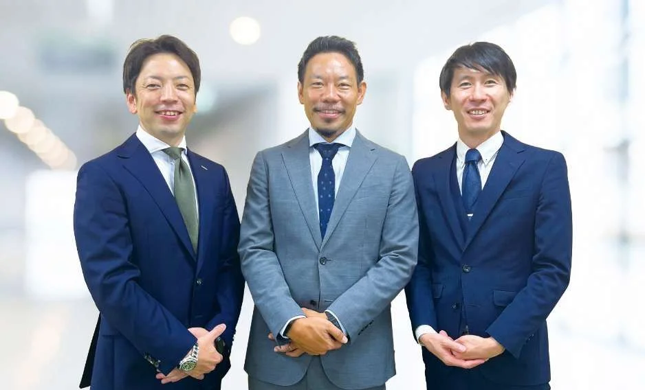 3人の男性社員がにこやかに微笑んでいる写真